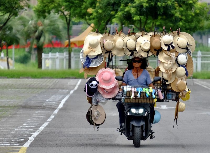 Wang Shang-chi, 75, a mobile hats vender, rides his bike on a parking lot next to the Taipei City Zoo. (Photo by Sam Yeh/AFP Photo)